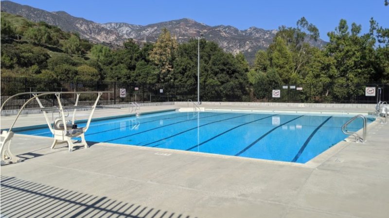 Loma Alta Park pool with trees and mountains behind and blue skies.