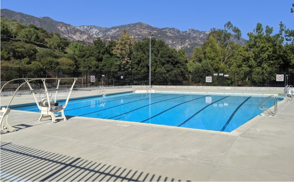Loma Alta Park pool with trees and mountains behind and blue skies.