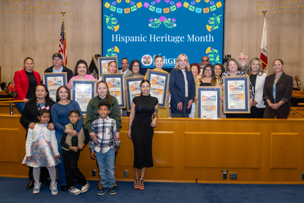 Hispanic Heritage Month honorees stand with their scrolls beside Supervisor Barger.